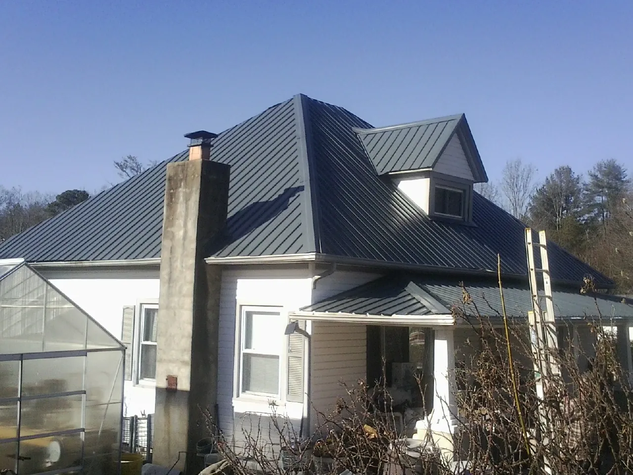 Dark blue standing seam metal roof on a white farmhouse with dormer — Slate & Tile Roof Repair by Roofing Brothers in Newton Center