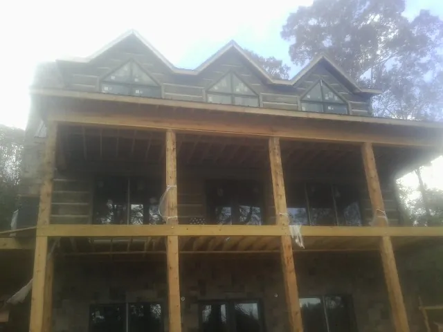 Dormers and porch framing on a large log home under construction — Roof Coating work by our crew in Newton Center