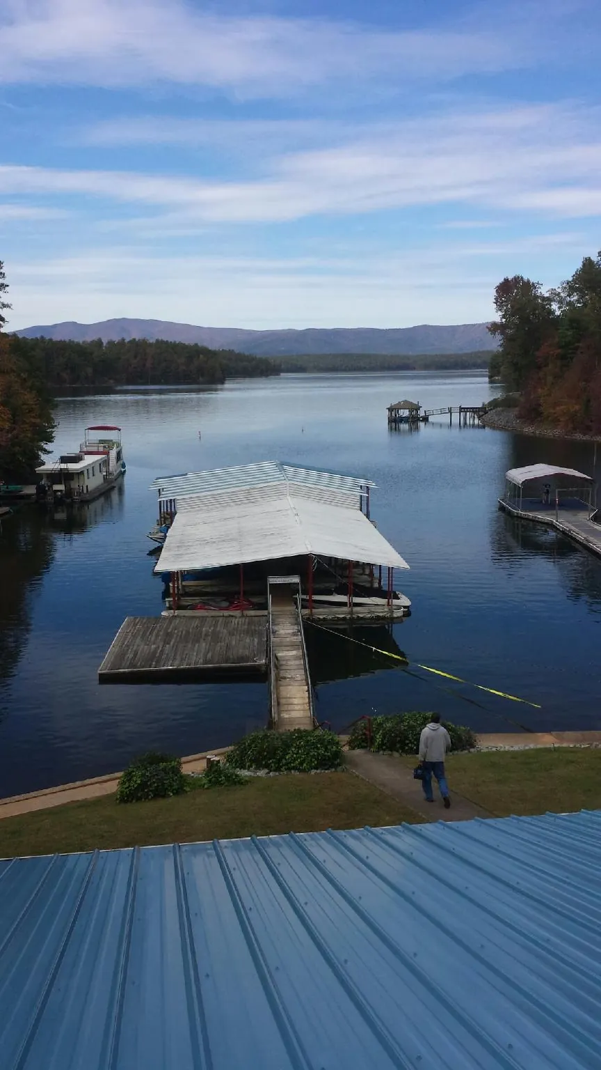 View across a lake from a newly installed blue metal roof in Newton Center