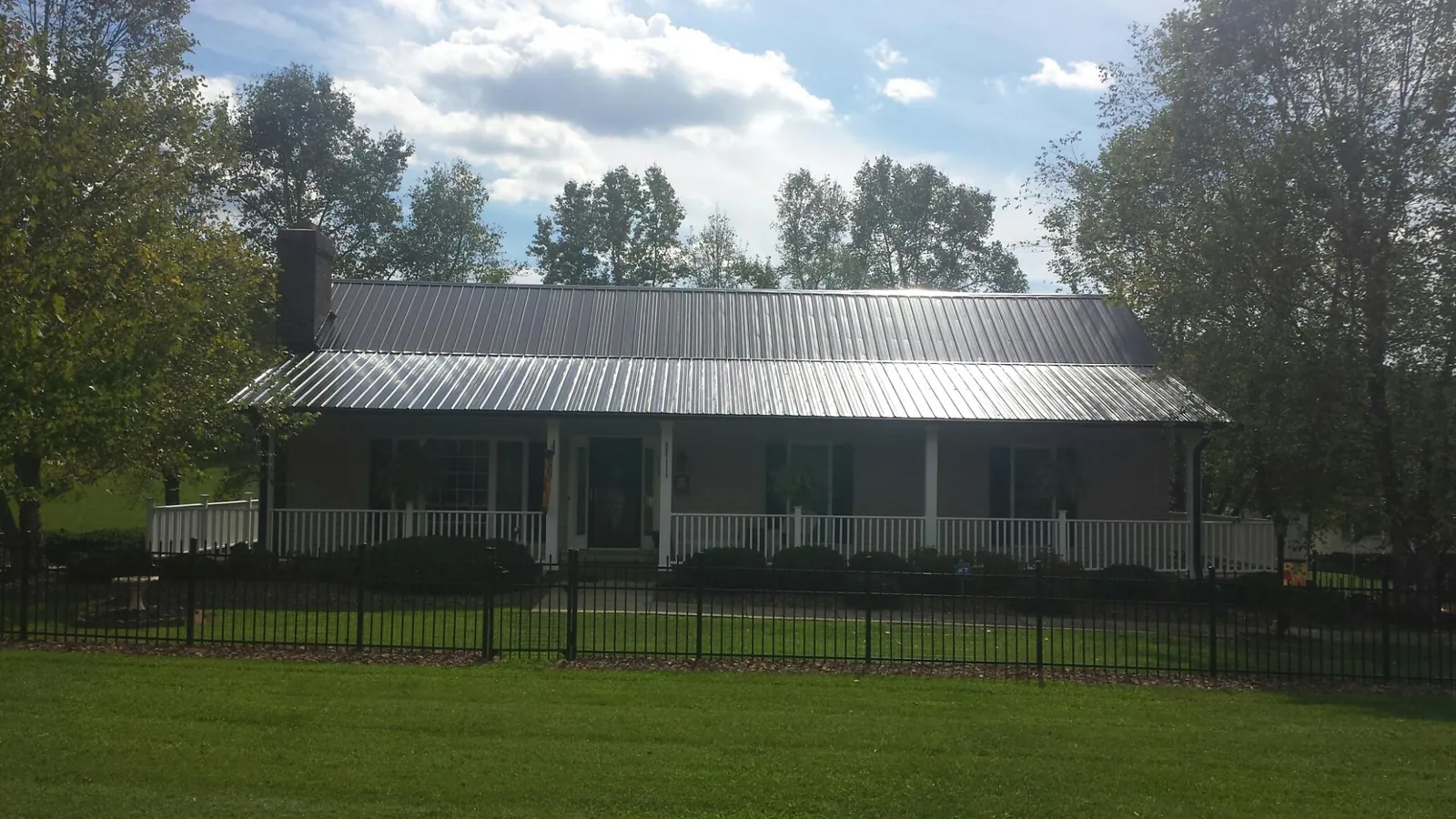 Gray metal roof on a brick ranch with a full width front porch — Gutter Guard Installation work by our crew in Newton Center