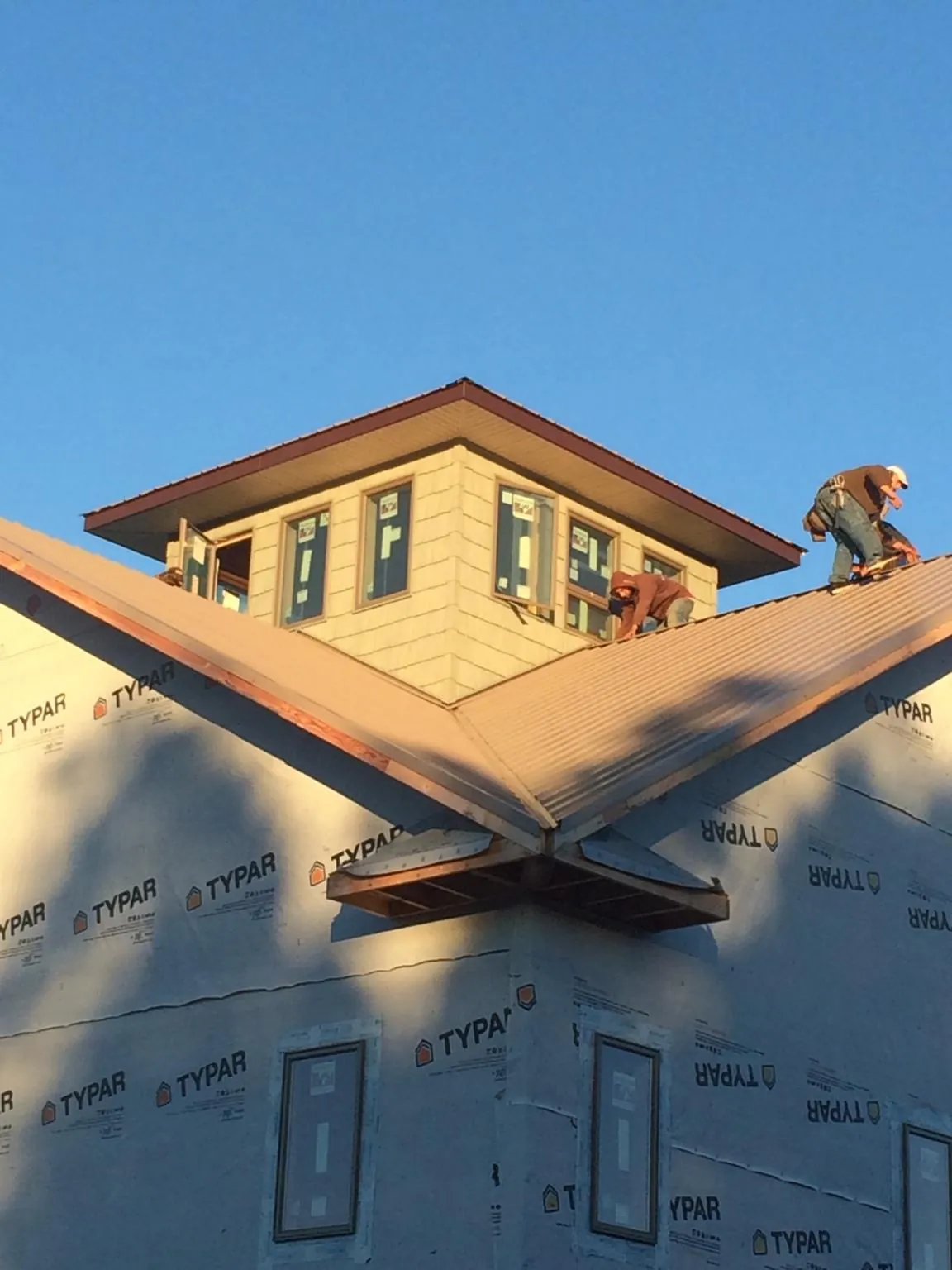 Roofers working around a rooftop cupola on a new metal roof at sunset — Roof Waterproofing in Newton Center by Roofing Brothers